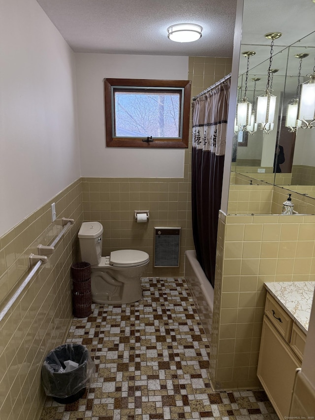 bathroom with toilet, a textured ceiling, tile walls, shower / tub combo, and vanity