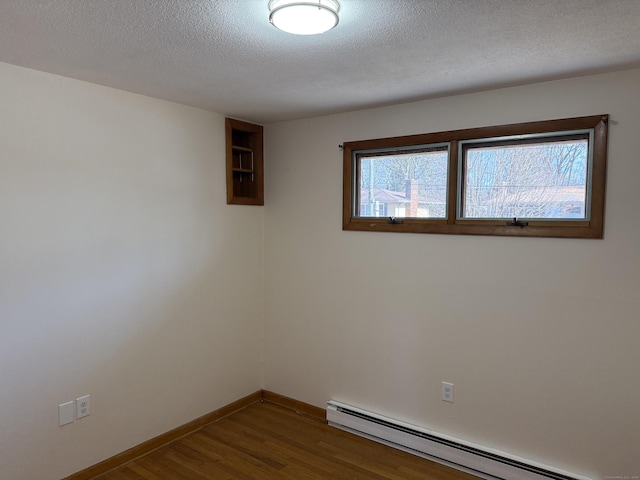 empty room featuring dark wood finished floors, a textured ceiling, baseboards, and a baseboard radiator