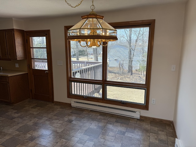 unfurnished dining area featuring a baseboard heating unit, plenty of natural light, a notable chandelier, and baseboard heating