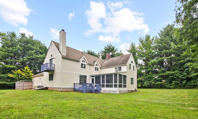 back of property featuring a yard, a deck, and a sunroom