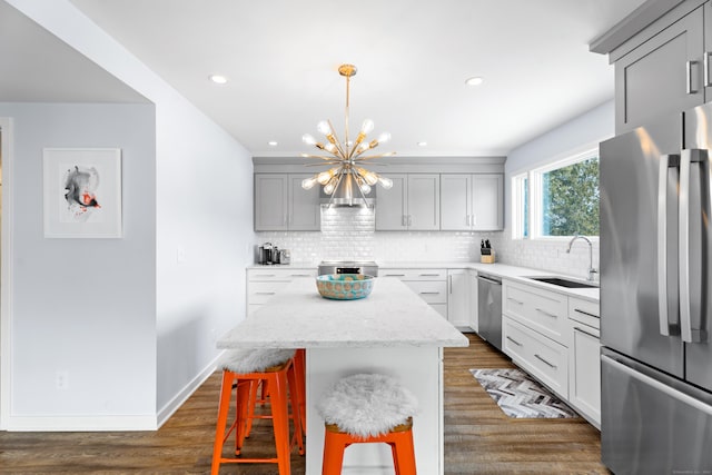 kitchen with gray cabinets, appliances with stainless steel finishes, sink, decorative backsplash, and a center island