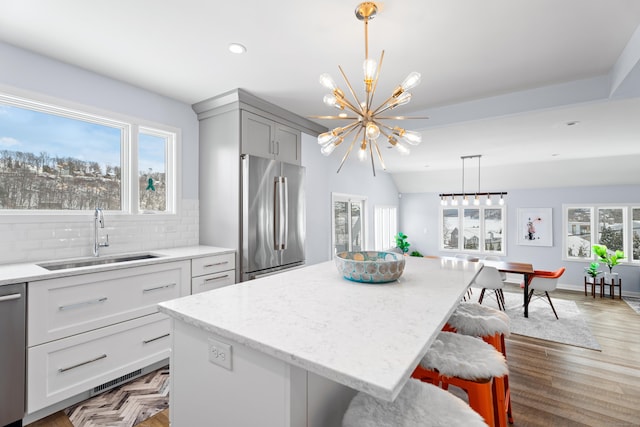 kitchen featuring stainless steel appliances, decorative light fixtures, a center island, and sink