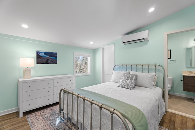 bedroom with ensuite bath, a wall mounted air conditioner, and dark parquet floors