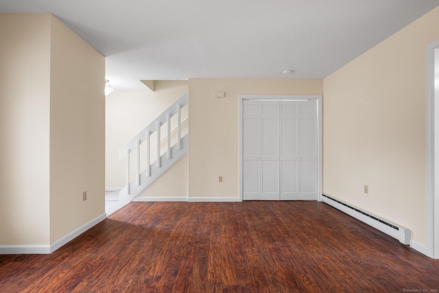 empty room with dark wood-type flooring and a baseboard heating unit