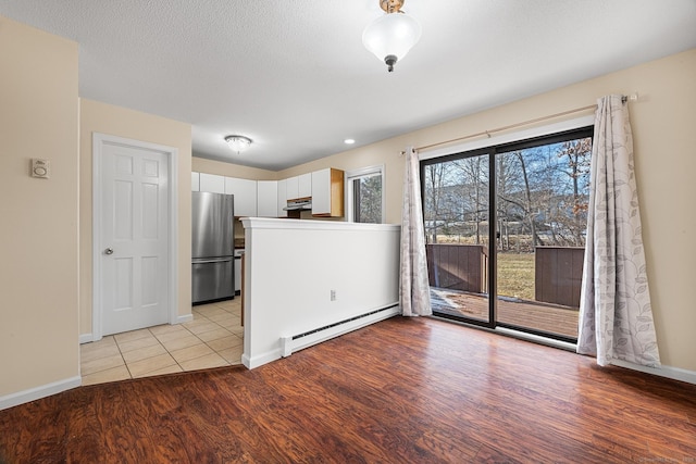 interior space with light hardwood / wood-style flooring, a baseboard radiator, and a textured ceiling