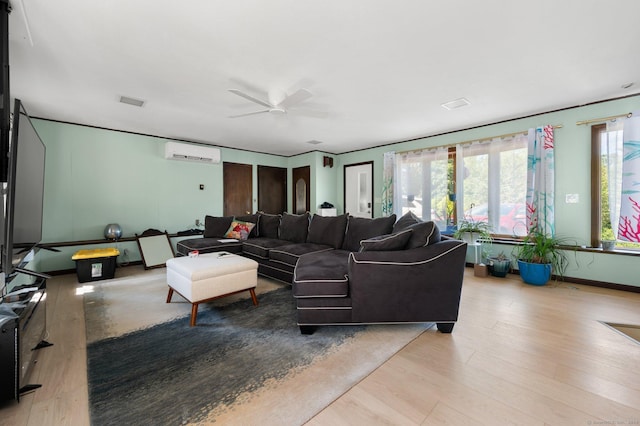 living room featuring a wealth of natural light, a wall mounted air conditioner, ceiling fan, and light hardwood / wood-style floors