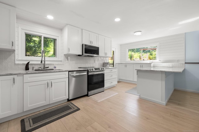 kitchen with white cabinetry, sink, stainless steel appliances, and light stone countertops