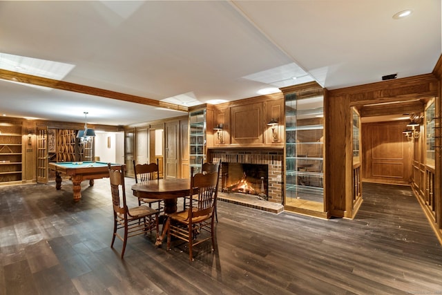 dining room with dark wood-type flooring, pool table, a fireplace, and wood walls