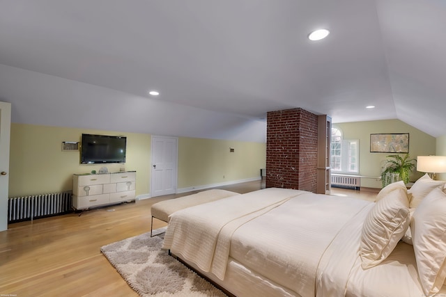 bedroom with vaulted ceiling, radiator heating unit, and light hardwood / wood-style floors