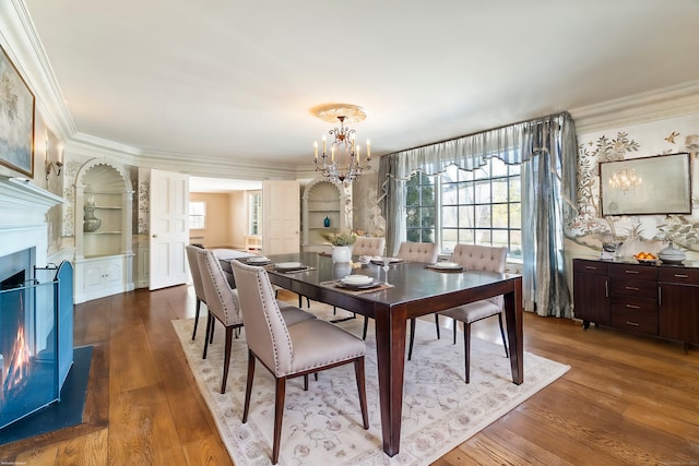 dining area with crown molding, dark hardwood / wood-style floors, an inviting chandelier, and built in features