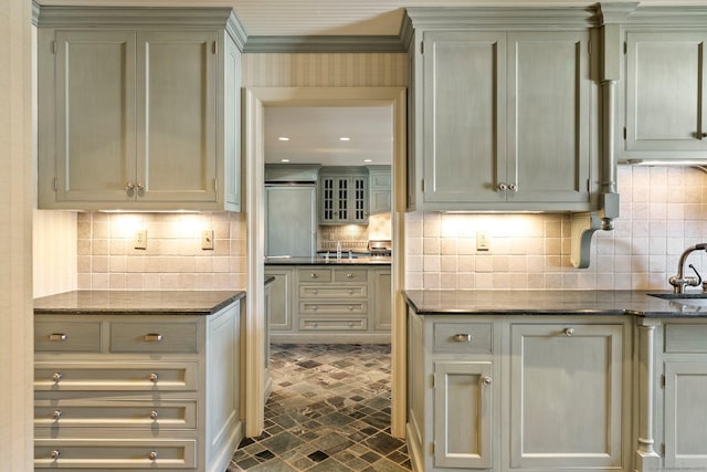 bar with backsplash, sink, cream cabinets, and dark stone counters