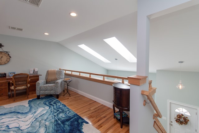 living area featuring lofted ceiling with skylight and hardwood / wood-style floors