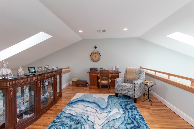 living area featuring lofted ceiling with skylight and hardwood / wood-style floors