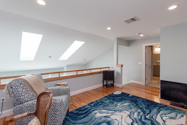 sitting room with wood-type flooring and vaulted ceiling with skylight