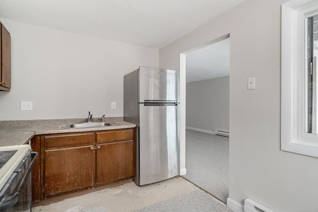 kitchen with stainless steel refrigerator, baseboard heating, sink, and white range oven