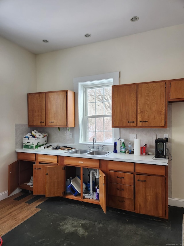 kitchen with tasteful backsplash, brown cabinets, light countertops, and a sink