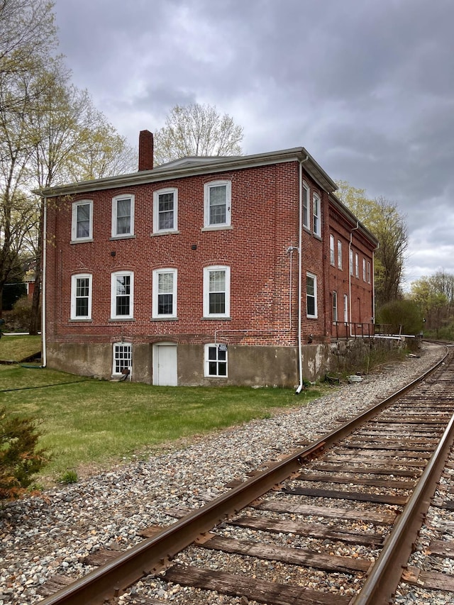 view of home's exterior featuring a lawn and a chimney