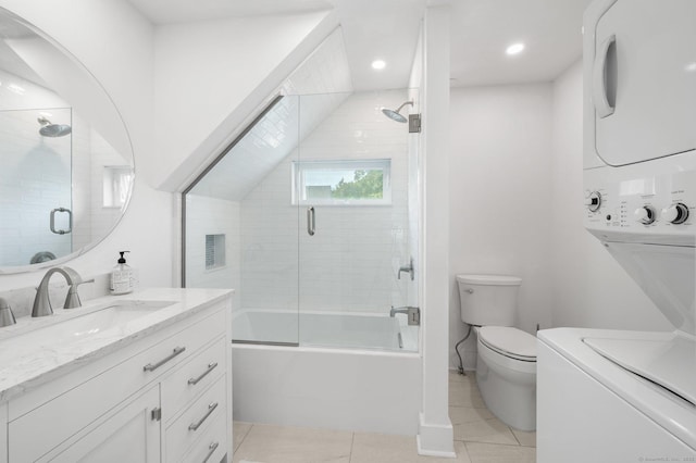 full bathroom featuring combined bath / shower with glass door, vanity, stacked washer and clothes dryer, toilet, and tile patterned floors