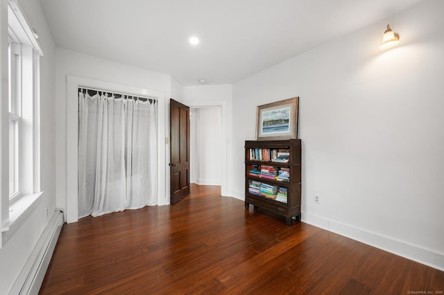 empty room featuring a baseboard heating unit and dark hardwood / wood-style floors