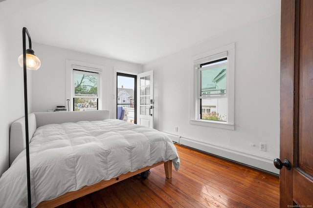 bedroom with a baseboard heating unit and wood-type flooring