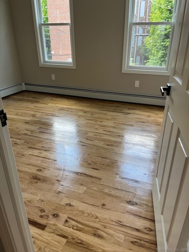 spare room with light hardwood / wood-style floors, a healthy amount of sunlight, and baseboard heating