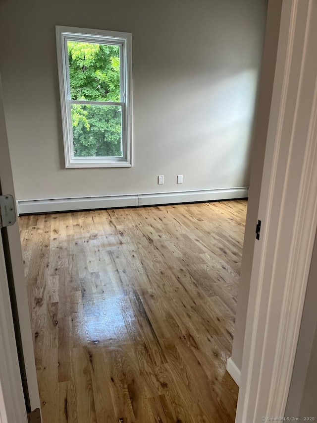 spare room with a baseboard radiator and light hardwood / wood-style flooring