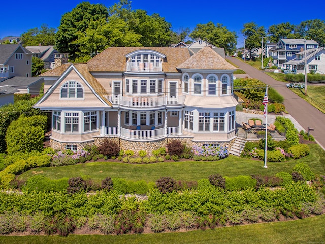 rear view of property with a balcony, a sunroom, and a lawn