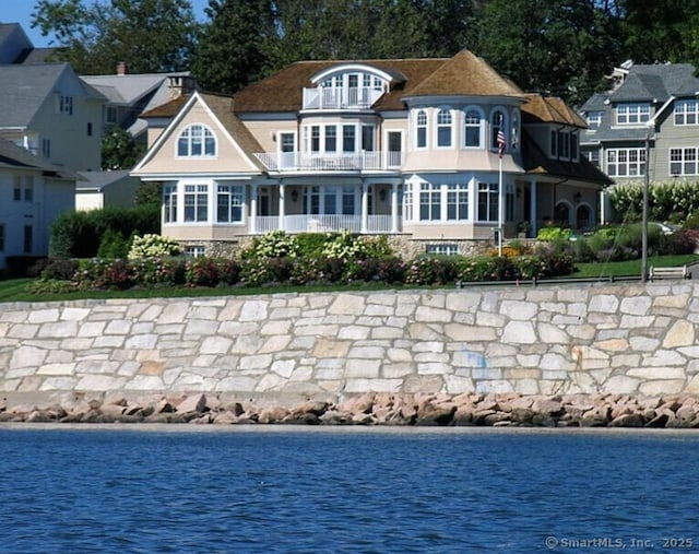 rear view of house with a water view and a balcony