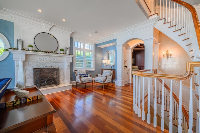 living room with crown molding, a premium fireplace, decorative columns, and hardwood / wood-style floors