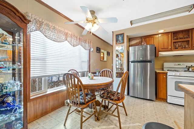 dining room with plenty of natural light, ornamental molding, ceiling fan, and wood walls