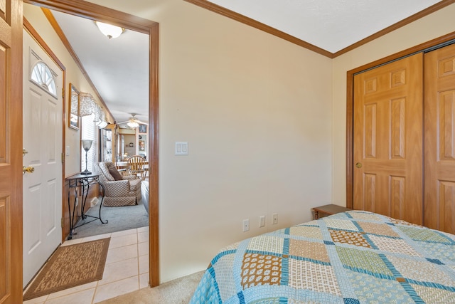 bedroom with light tile patterned floors, ornamental molding, and a closet