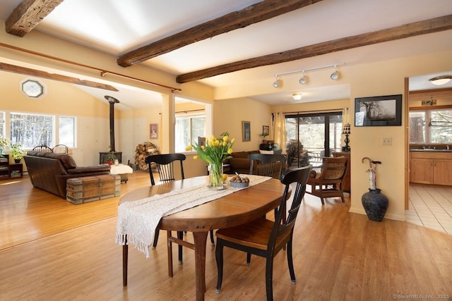 dining room featuring a wealth of natural light, light wood-type flooring, and a wood stove