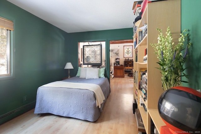 bedroom with baseboard heating and light hardwood / wood-style flooring