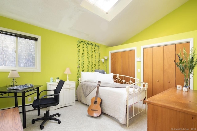 bedroom featuring two closets, carpet floors, and lofted ceiling with skylight