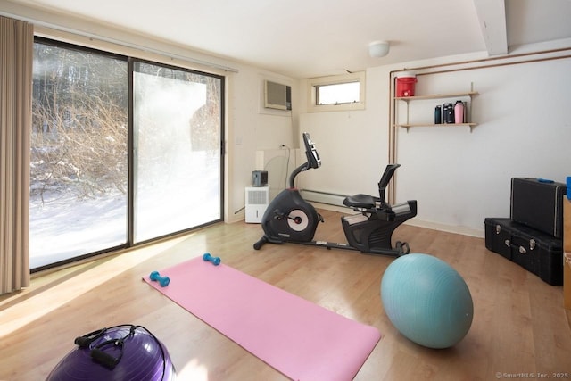 exercise area with wood-type flooring, a wealth of natural light, and a wall unit AC