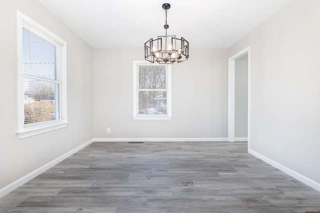 unfurnished dining area with a notable chandelier and dark hardwood / wood-style floors