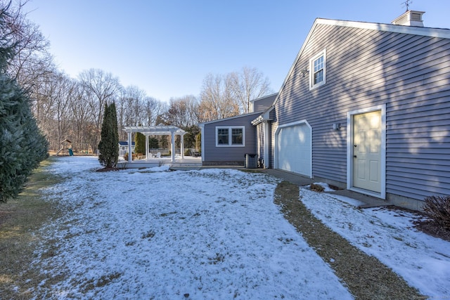 yard covered in snow with a garage and a pergola