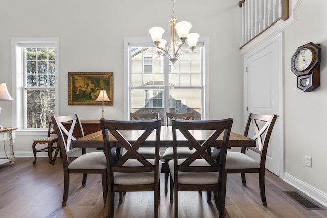 dining space with dark wood-type flooring and an inviting chandelier