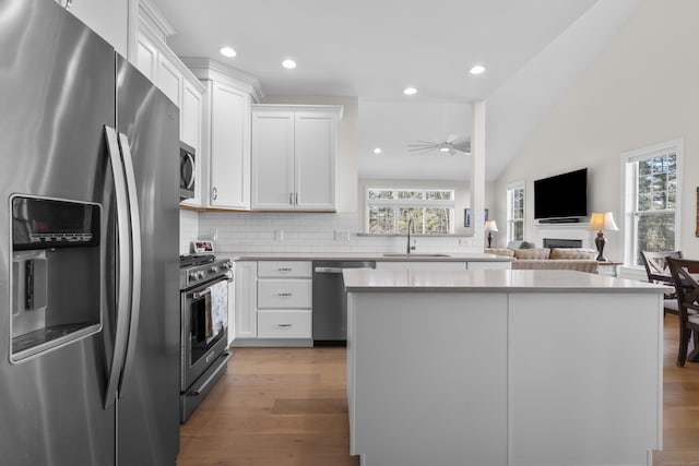 kitchen with tasteful backsplash, white cabinetry, sink, light hardwood / wood-style floors, and stainless steel appliances