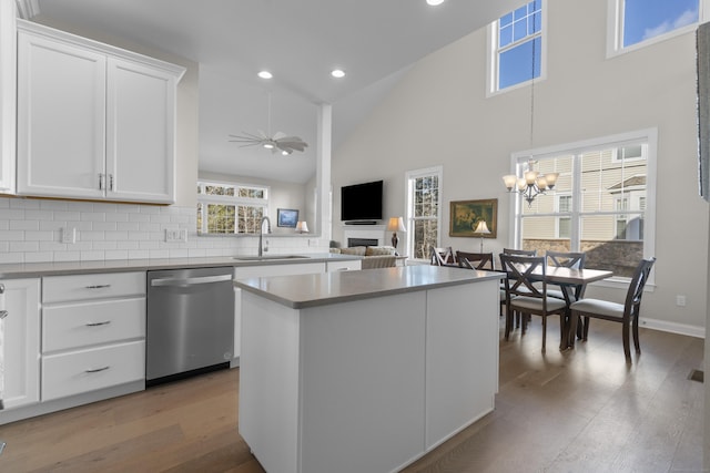 kitchen with ceiling fan with notable chandelier, dishwasher, sink, white cabinets, and a center island