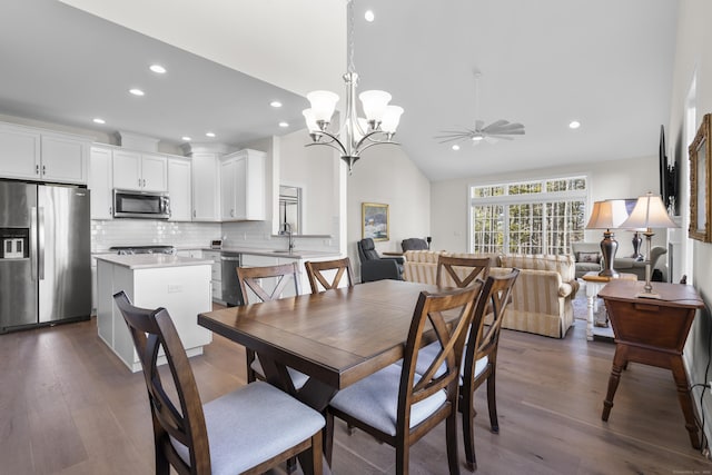 dining space featuring lofted ceiling, ceiling fan with notable chandelier, and dark wood-type flooring