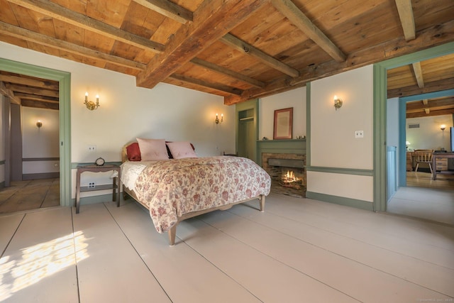 bedroom featuring beam ceiling, wood ceiling, and a fireplace