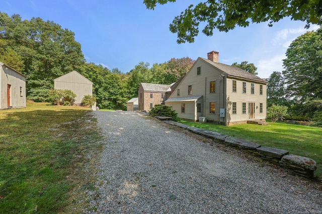 view of home's exterior featuring cooling unit, a storage shed, and a lawn