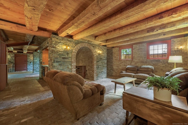 living room featuring wood ceiling, a fireplace, beamed ceiling, and brick wall