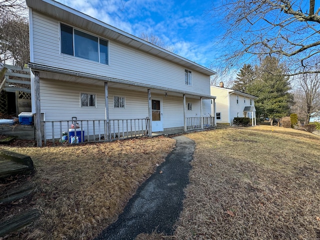 rear view of house featuring covered porch and a yard