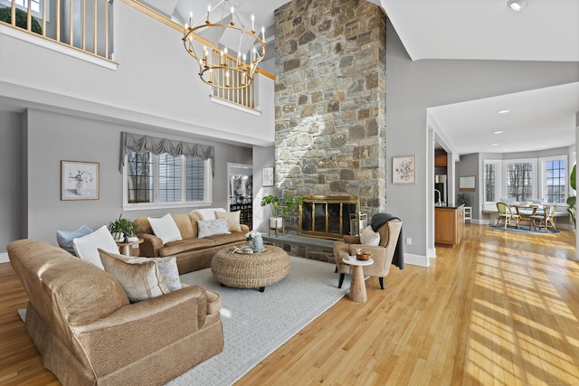 living area with light wood finished floors, baseboards, a fireplace, and a chandelier