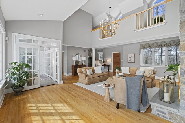 living room featuring high vaulted ceiling, baseboards, stairs, wood-type flooring, and an inviting chandelier