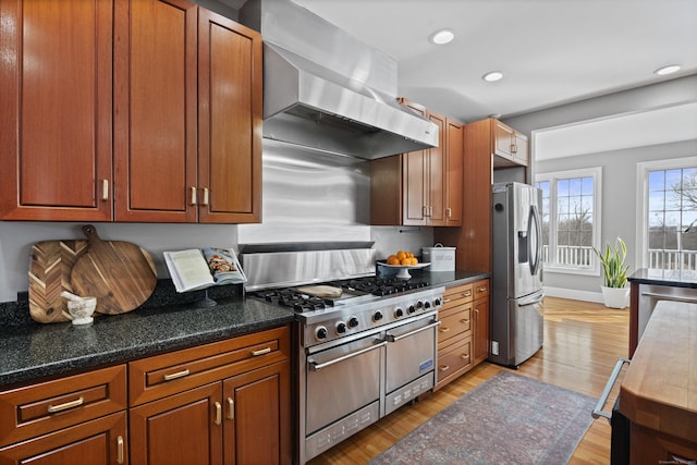 kitchen featuring brown cabinetry, light wood-style flooring, appliances with stainless steel finishes, range hood, and recessed lighting