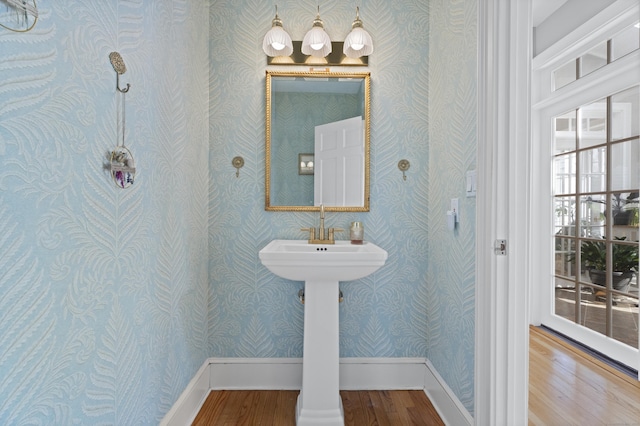 bathroom featuring baseboards, wood finished floors, and wallpapered walls