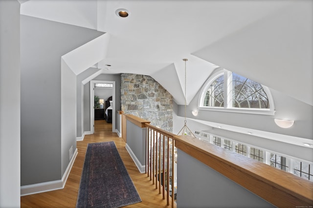 hall with lofted ceiling, baseboards, an upstairs landing, and wood finished floors